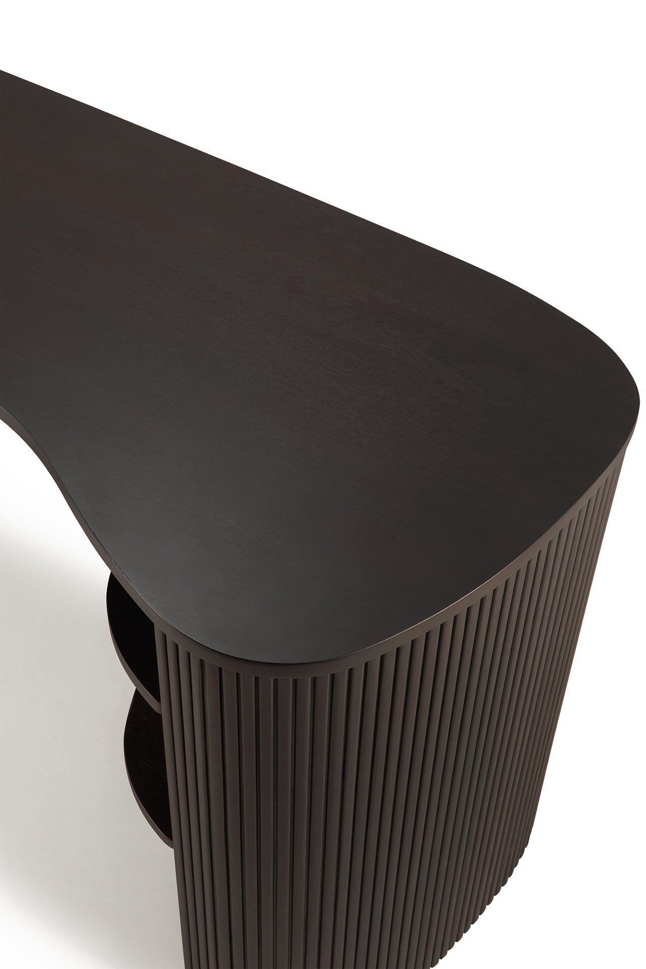 The Ethnicraft Roller Max Desk, shown overhead against a white background, features dark mahogany wood, a curved asymmetrical top, and vertical slatted sides.