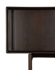 Close-up of the Flow Sideboard by Ethnicraft, featuring dark mahogany, a smooth rectangular surface with rounded edges, and a single cylindrical leg—blending sleek minimalism and vintage modern style.