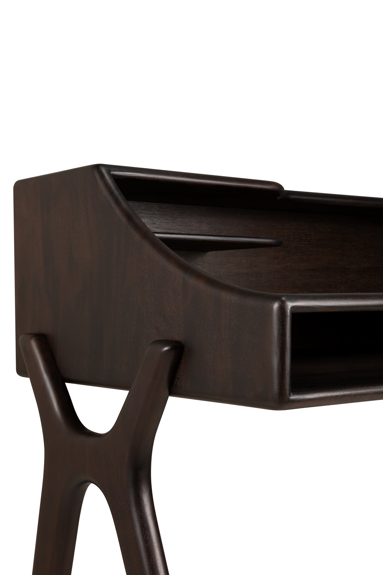 The Flow Desk by Ethnicraft is a modern dark wood desk with angled legs and an open storage compartment, featuring smooth rounded edges and a sculptural, contemporary design.