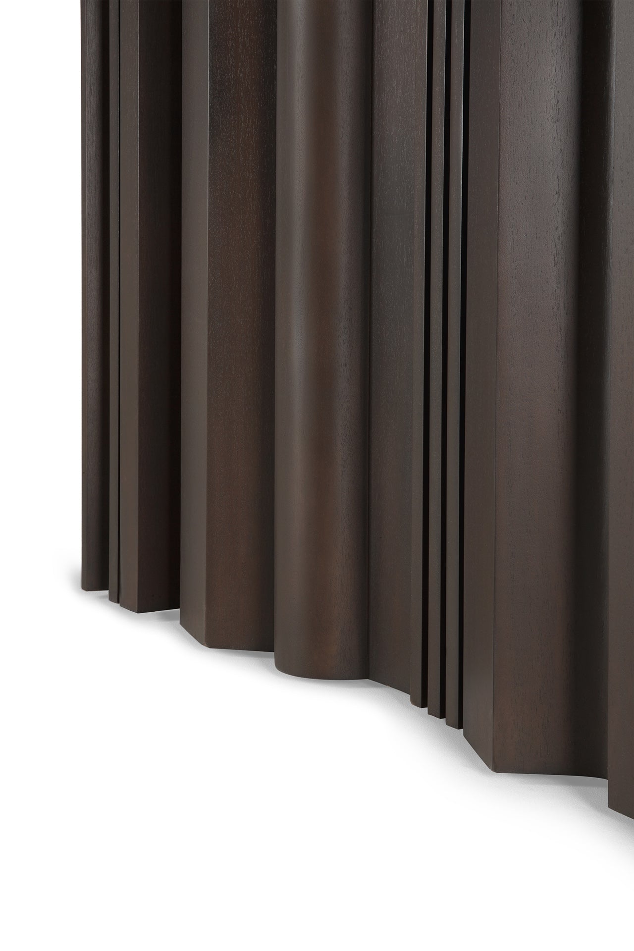 Close-up of Ethnicraft's Sequence Dining Table shows dark brown mahogany wood with vertical, uneven curved and straight panels that create a sculptural, layered look against a white background.