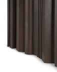 Close-up of Ethnicraft's Sequence Dining Table shows dark brown mahogany wood with vertical, uneven curved and straight panels that create a sculptural, layered look against a white background.