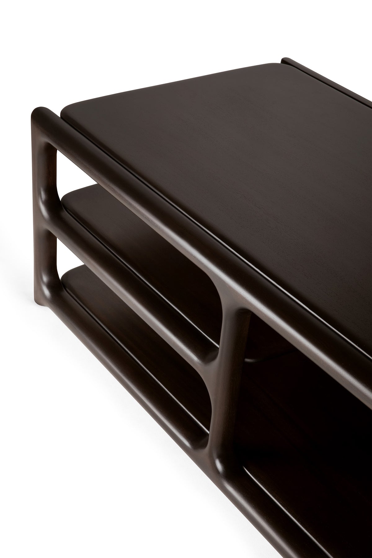 A close-up of the Ethnicraft Eda Coffee Table showcases its modern design, featuring dark wood construction with rounded edges and two open shelves beneath the tabletop—an heirloom-quality piece inspired by European craftsmanship.