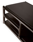 A close-up of the Ethnicraft Eda Coffee Table showcases its modern design, featuring dark wood construction with rounded edges and two open shelves beneath the tabletop—an heirloom-quality piece inspired by European craftsmanship.