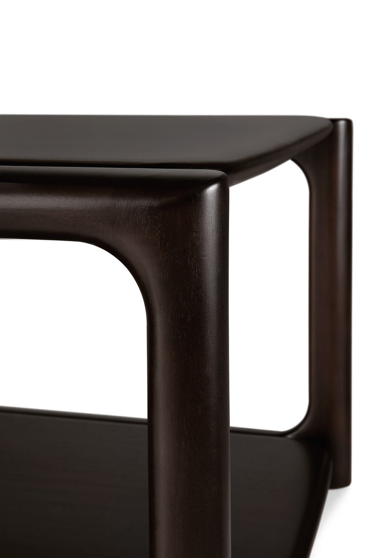 Close-up of the Ethnicraft Eda Coffee Table, a modern piece crafted from dark wood with rounded edges and gracefully curved legs, featuring a lower shelf beneath the tabletop. This elegant design is a testament to European craftsmanship and Ethnicraft’s commitment to creating heirloom-quality furniture perfectly suited for contemporary spaces.