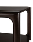 Close-up of the Ethnicraft Eda Coffee Table, a modern piece crafted from dark wood with rounded edges and gracefully curved legs, featuring a lower shelf beneath the tabletop. This elegant design is a testament to European craftsmanship and Ethnicraft’s commitment to creating heirloom-quality furniture perfectly suited for contemporary spaces.