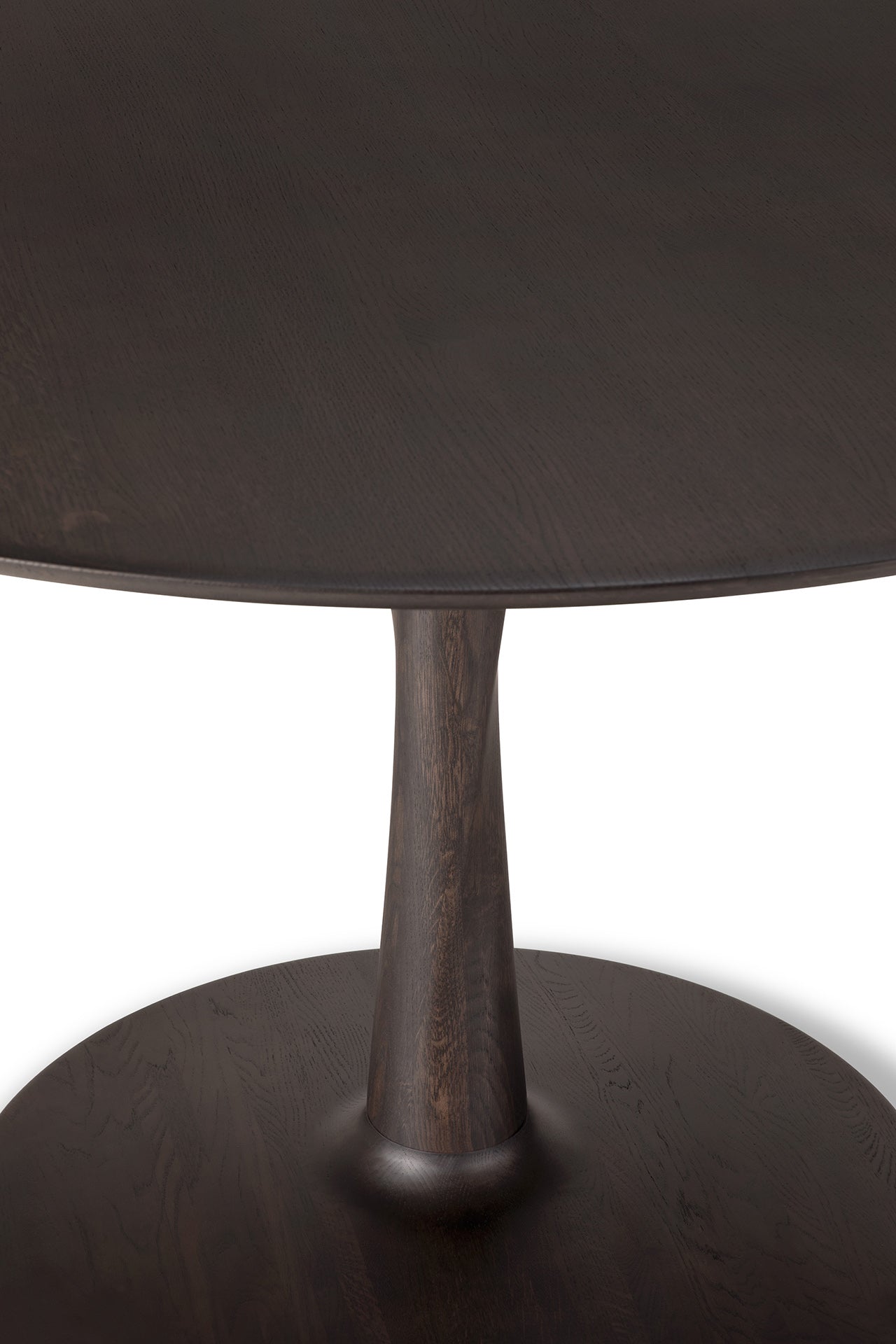 A close-up of the Ethnicraft Torsion Dining Table in oak brown, featuring a single thick central pedestal base, set against a white background.