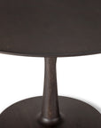 A close-up of the Ethnicraft Torsion Dining Table in oak brown, featuring a single thick central pedestal base, set against a white background.
