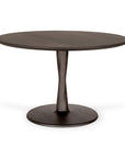 The Ethnicraft Torsion Dining Table - Oak Brown is a round, sculptural oak table with a curved pedestal base and flat circular bottom, showcased against a white background.