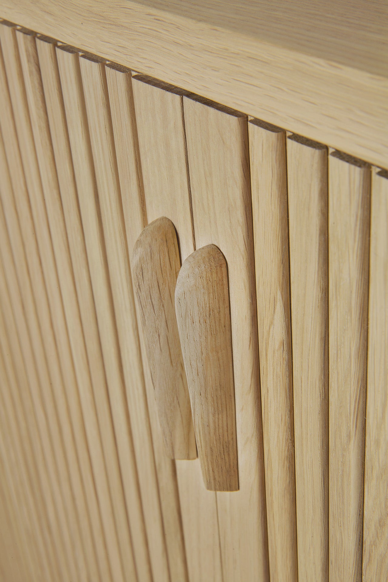 Close-up of the Ethnicraft Roller Max Sideboard in light wood, showcasing vertical slats, two matching wooden handles, and a natural solid oak texture with clean modern lines.