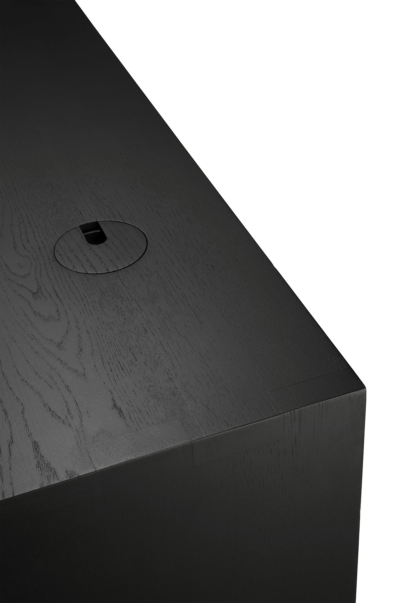 Close-up of the Ethnicraft U Desk - Black Oak, showing a circular cable management hole with cover near the edge and visible solid oak wood grain on the surface.
