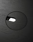 Close-up of Ethnicraft’s U Desk - Black Oak, showing its distinct wood grain, black oak finish, circular cutout, and oval slot contrasted against a white background.