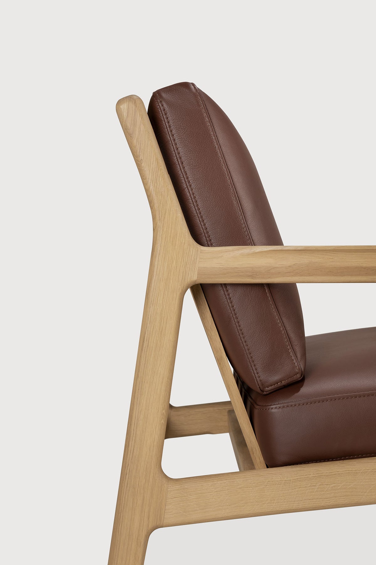 Side view of an Ethnicraft Jack Lounge Chair - Burgundy Leather with solid oak frame and burgundy leather cushions.