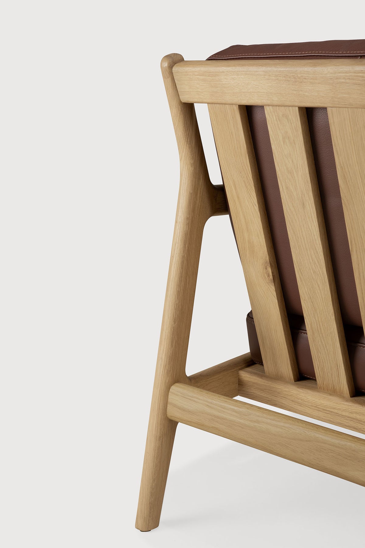 Close-up of the solid oak frame and backrest of an Ethnicraft Jack Lounge Chair - Burgundy Leather with burgundy leather cushions.