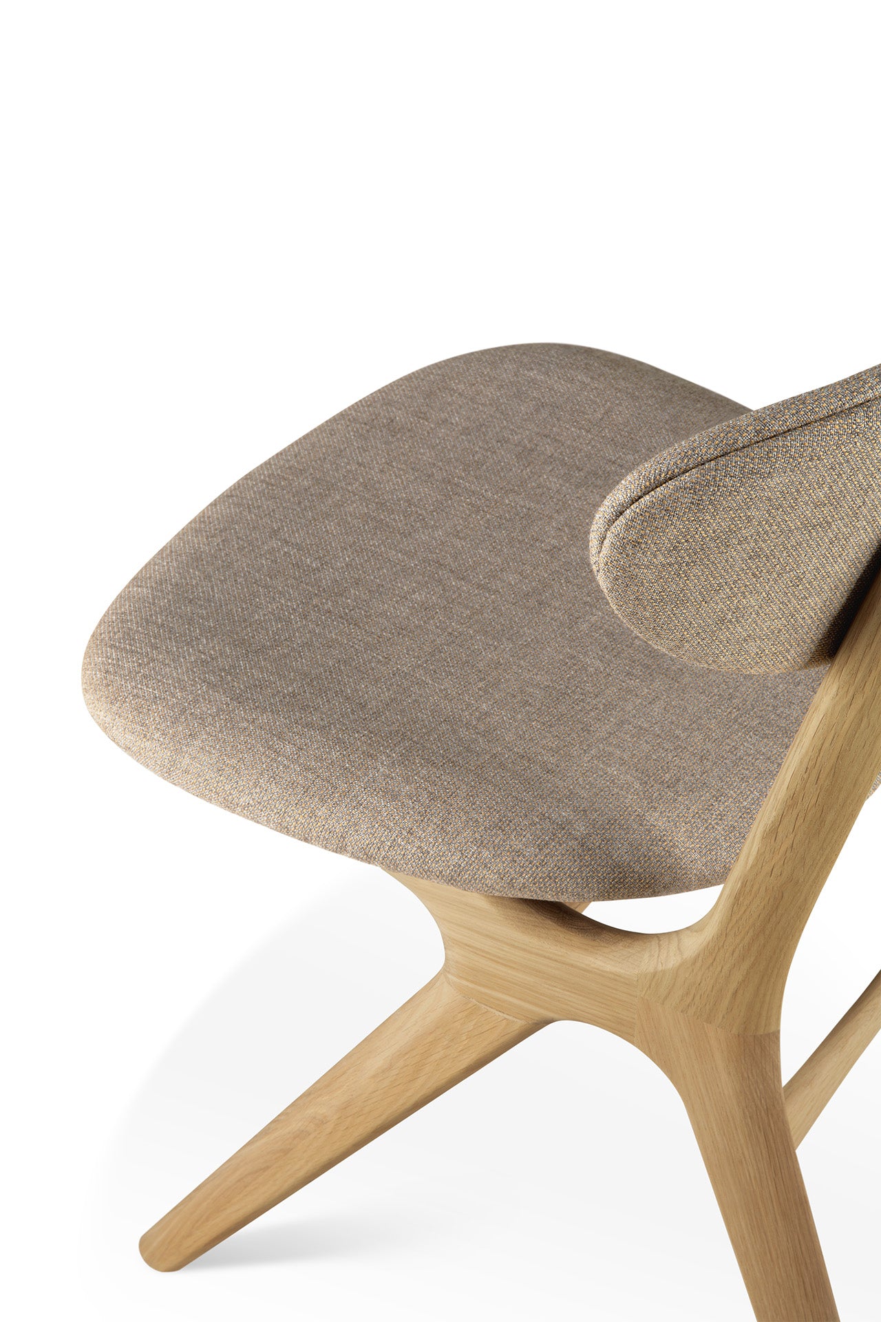 A close-up of the Ethnicraft Eye Dining Chair - Oak with Warm Grey Fabric highlights its solid oak frame, warm grey upholstered seat, and gracefully curved backrest, all set against a white background.