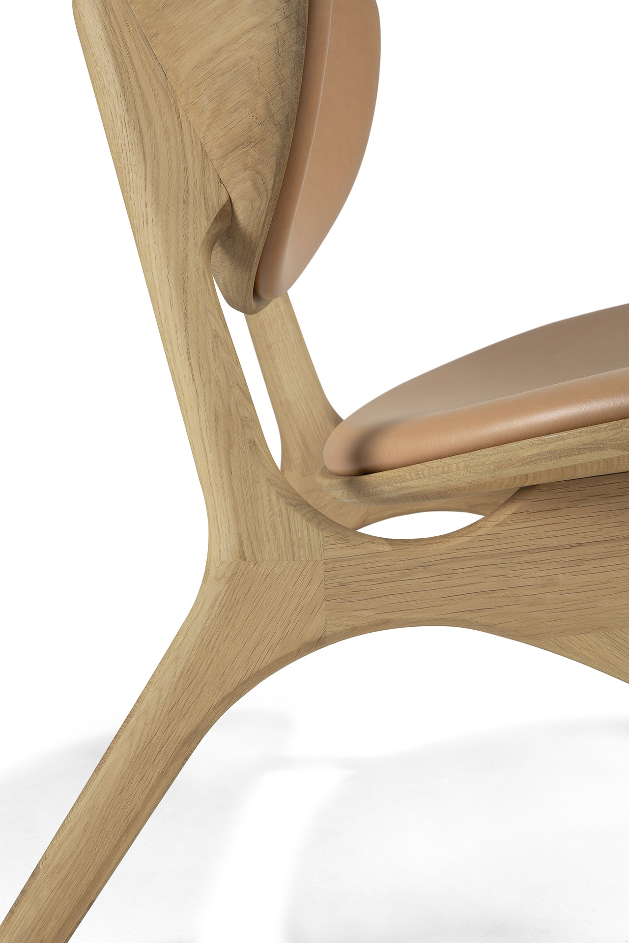 Close-up of the Ethnicraft Eye Lounge Chair – Oak with Leather, showcasing its smooth solid oak frame, Sienna leather seat and backrest, and elegant curves highlighting expert craftsmanship.