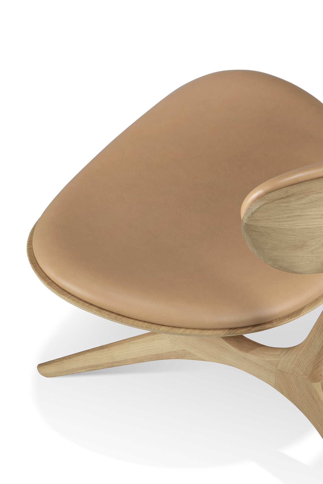 A close-up of the Ethnicraft Eye Lounge Chair - Oak with Leather, featuring a smooth Sienna leather seat and backrest, solid oak legs, and curved armrests, photographed against a white background.