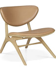 The Ethnicraft Eye Lounge Chair - Oak with Leather features a light solid oak frame, Sienna leather upholstery on the seat and backrest, and showcases curved lines with an angled, minimalist modern design.