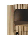 Close-up of the Ethnicraft Boomerang Drawer Unit - Oak, featuring vertical grooves, an open shelf, and a small round black knob on the lower compartment. The solid oak has a light, natural finish.