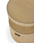 The Ethnicraft Boomerang Drawer Unit - Oak is a round wooden coffee table with solid oak, fluted sides, an open shelf, a smooth top, and a side handle that hints at its concealed storage compartment.