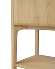 Close-up of the Ethnicraft PI Cupboard - Oak, featuring smooth, rounded legs, a lower shelf, and visible wood grain that highlights its minimalist design and handcrafted storage furniture quality.