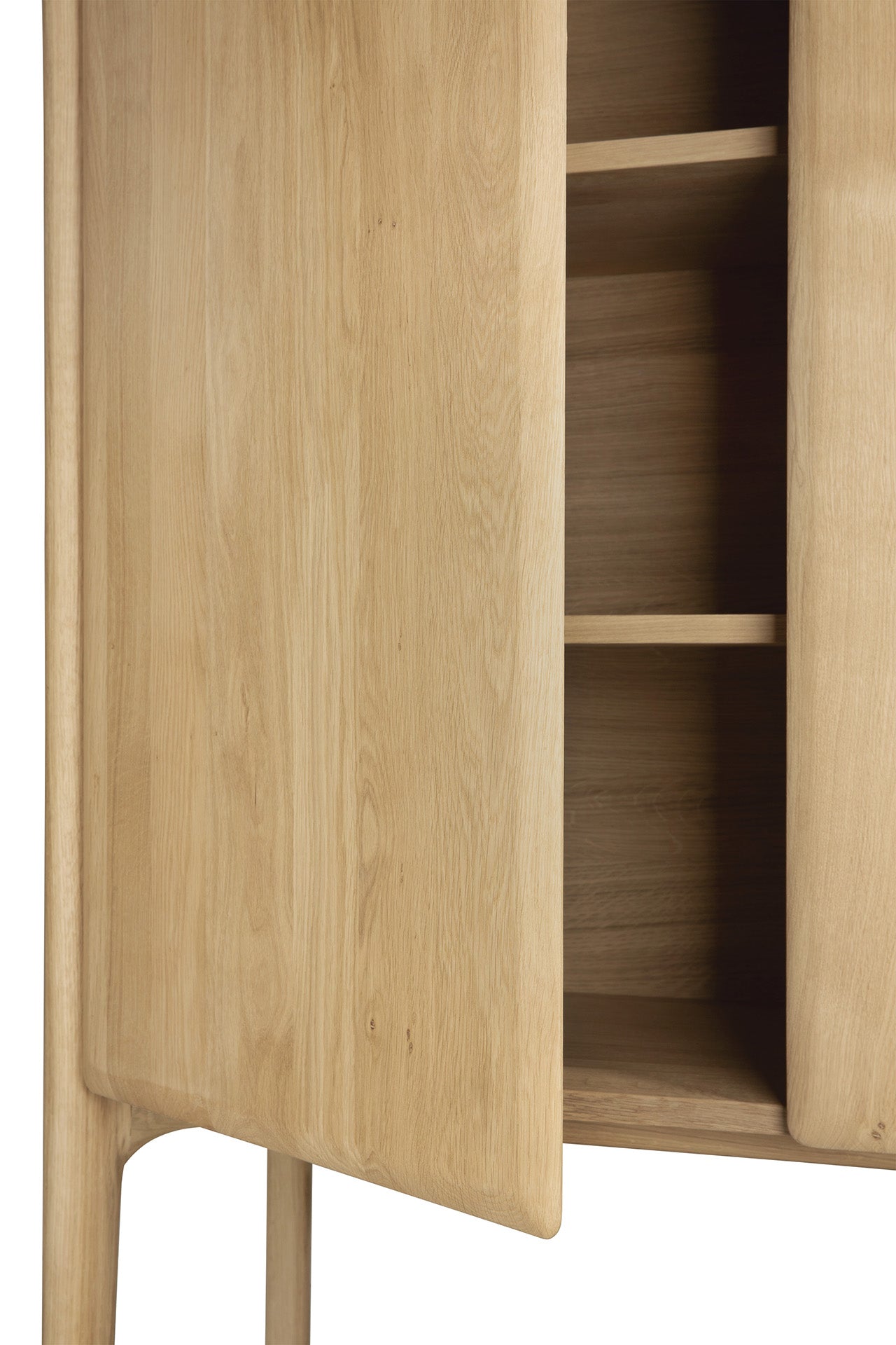 Close-up of the Ethnicraft PI Cupboard - Oak, handcrafted with smooth, rounded edges and a natural wood grain finish. A partially open door reveals three interior shelves in this solid oak storage piece.