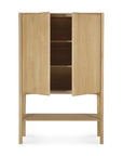 The Ethnicraft PI Cupboard - Oak features two doors, two interior shelves, a lower open shelf, and stands on four legs. Crafted from solid oak, it boasts a simple, modern design.