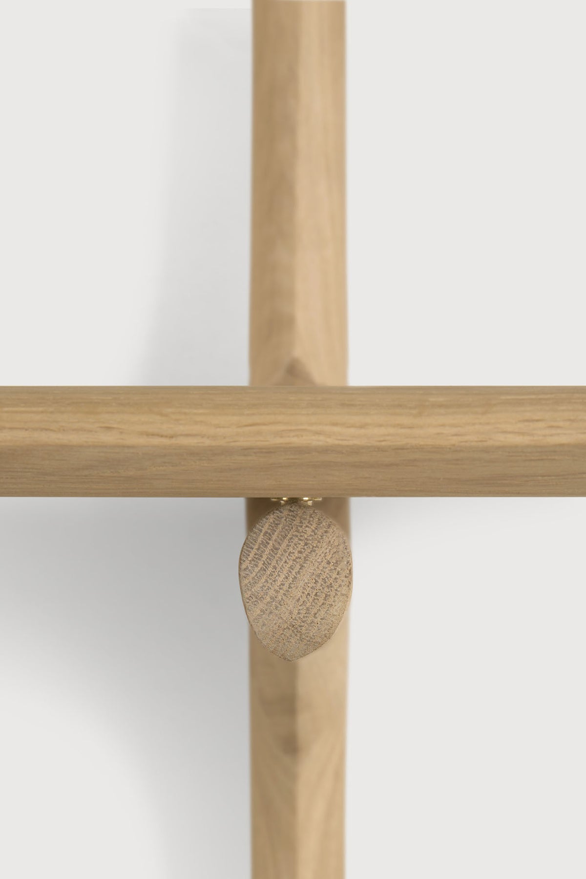 Close-up of a light solid oak Ethnicraft PI Wall Mounted Desk featuring an intersecting support structure joined by a small wooden oval-shaped fastener.