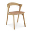 The Ethnicraft Bok Dining Chair features solid oak construction, a curved backrest, four legs, and a Sienna leather upholstered seat.