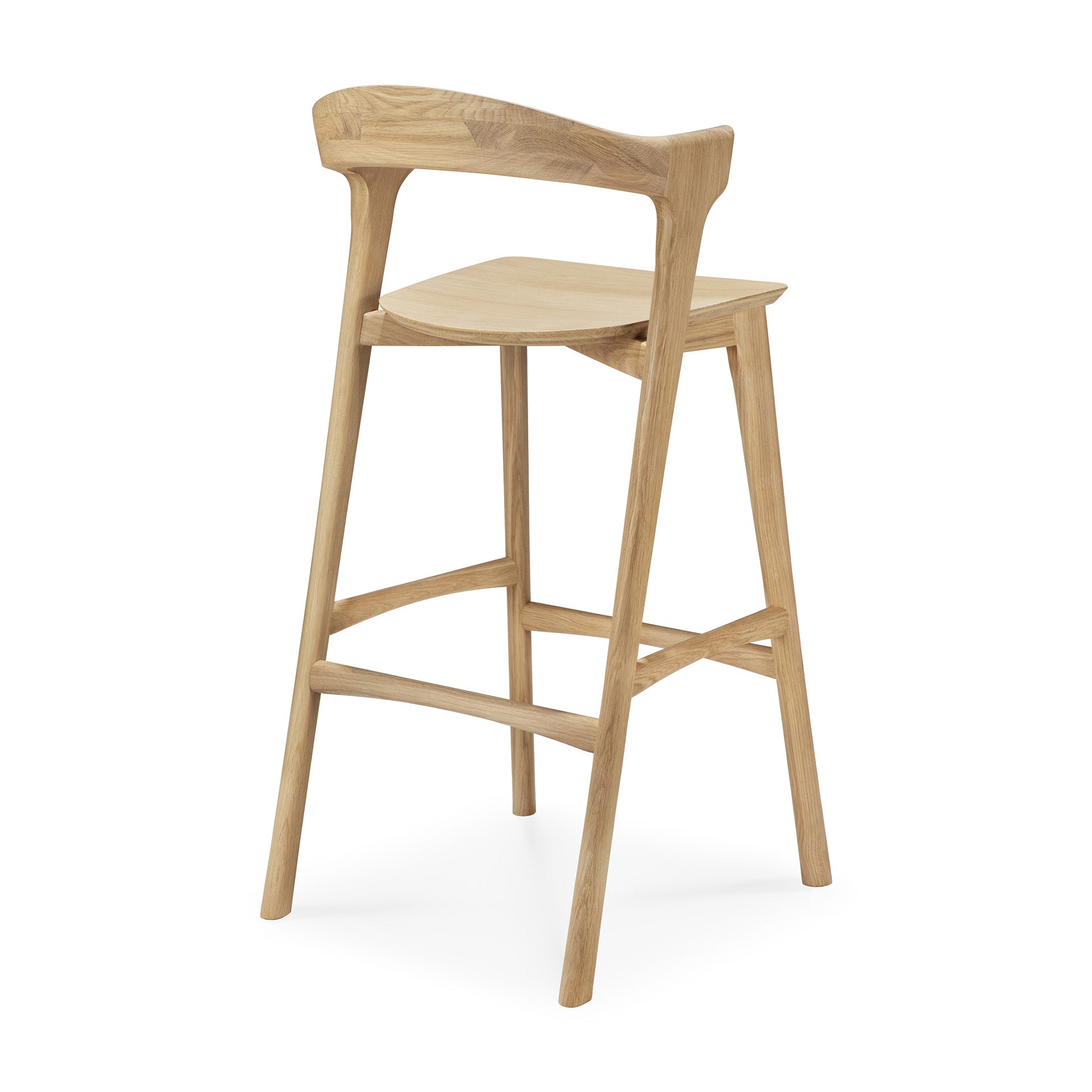 The Ethnicraft Bok bar stool in oak features a contoured seat, curved backrest, angled legs, and sturdy footrests. Crafted from solid oak with a simple natural finish, it combines modern design with comfort and support.
