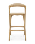 The Ethnicraft Bok bar stool - Oak features a curved backrest and seat, four legs, and two footrests. Its solid oak finish highlights a simple, modern design.