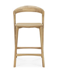 The Bok counter stool by Ethnicraft features a solid oak build, curved backrest, square seat, and tapered legs with support bars. Its natural finish and minimalist design complement the modern style of the Bok dining chair.