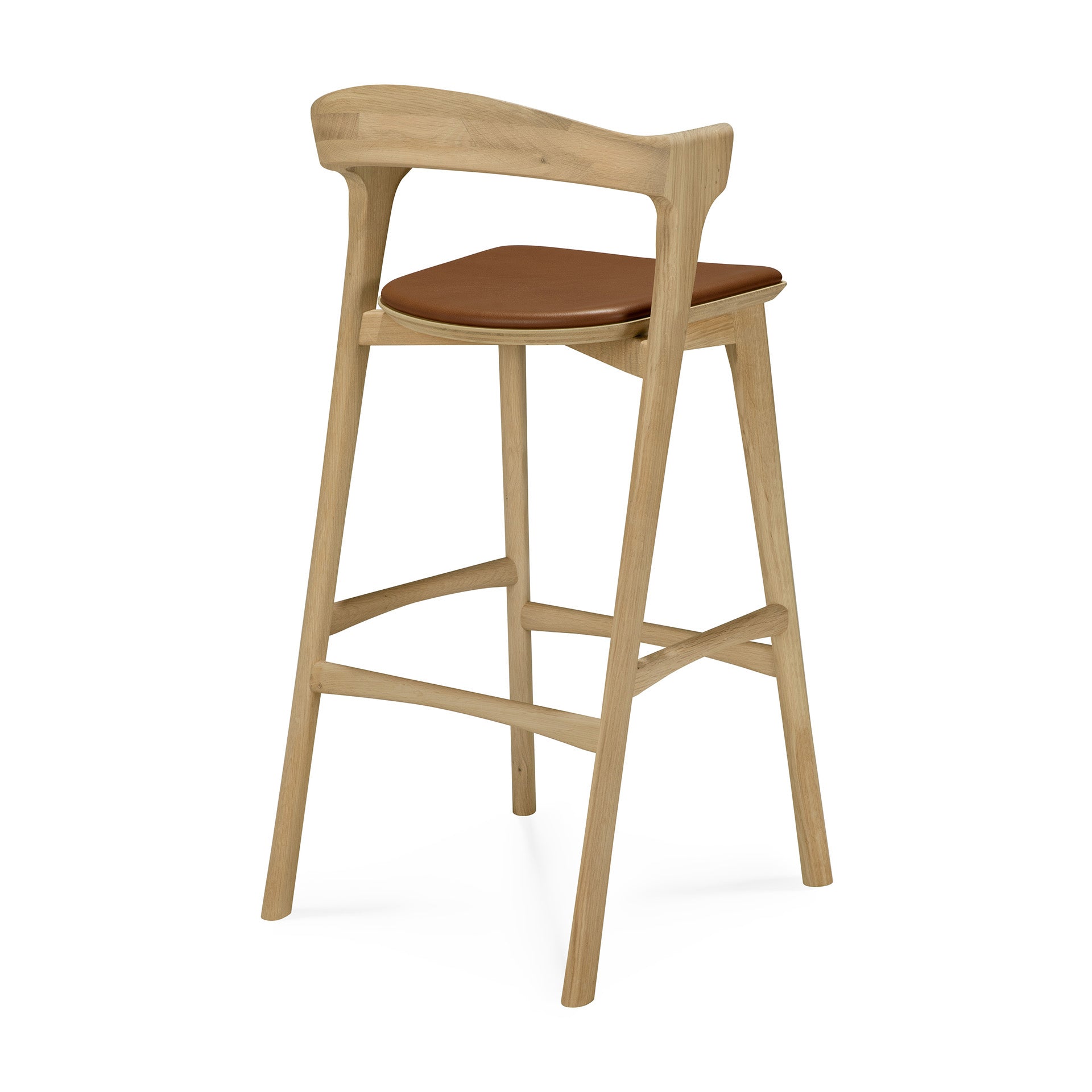 The Bok bar stool - Oak by Ethnicraft features a solid oak frame, angled legs, curved backrest, and a modern open design with a brown cushioned seat.