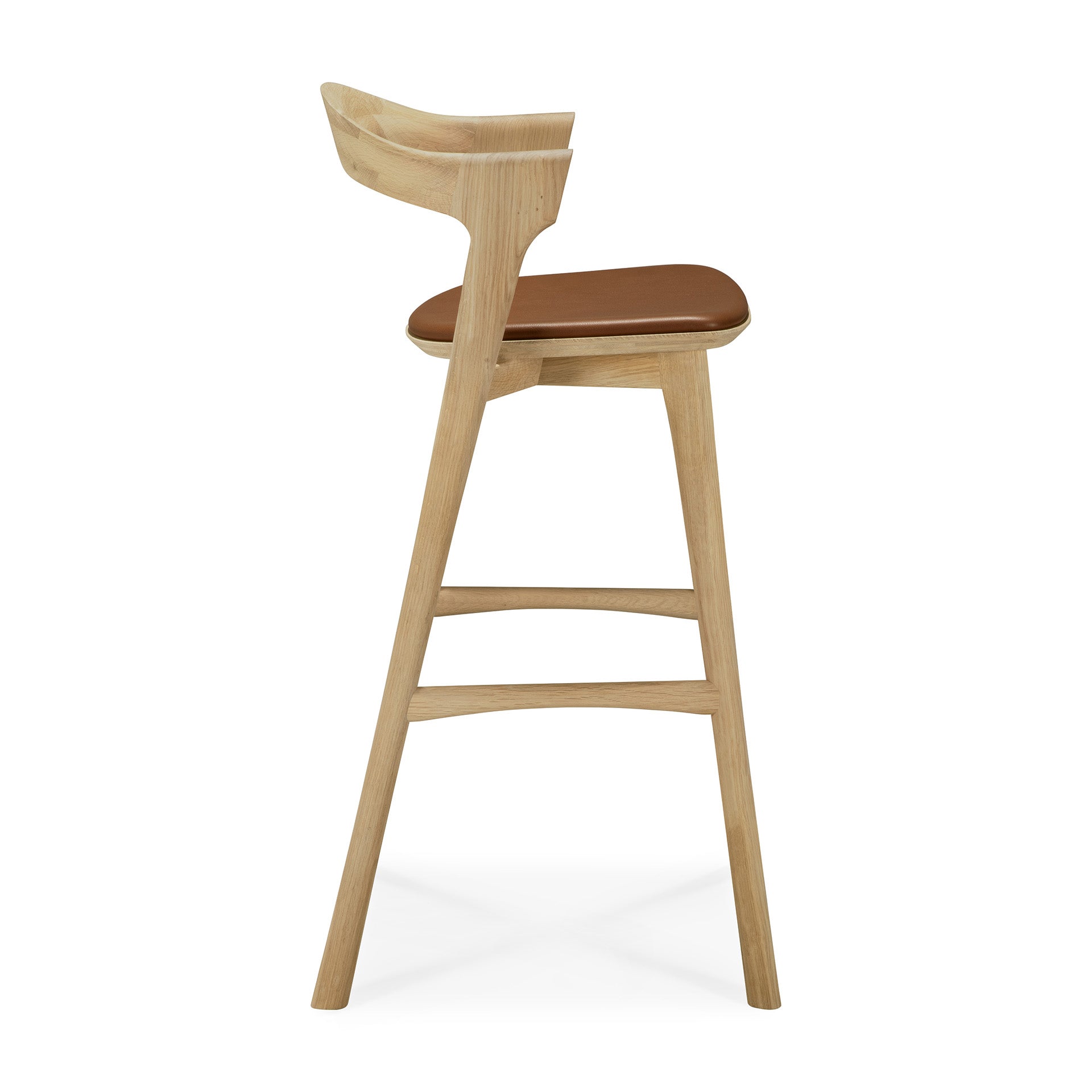 Side view of the Ethnicraft Bok bar stool in solid oak with a curved backrest and brown cushioned seat, set against a white background.