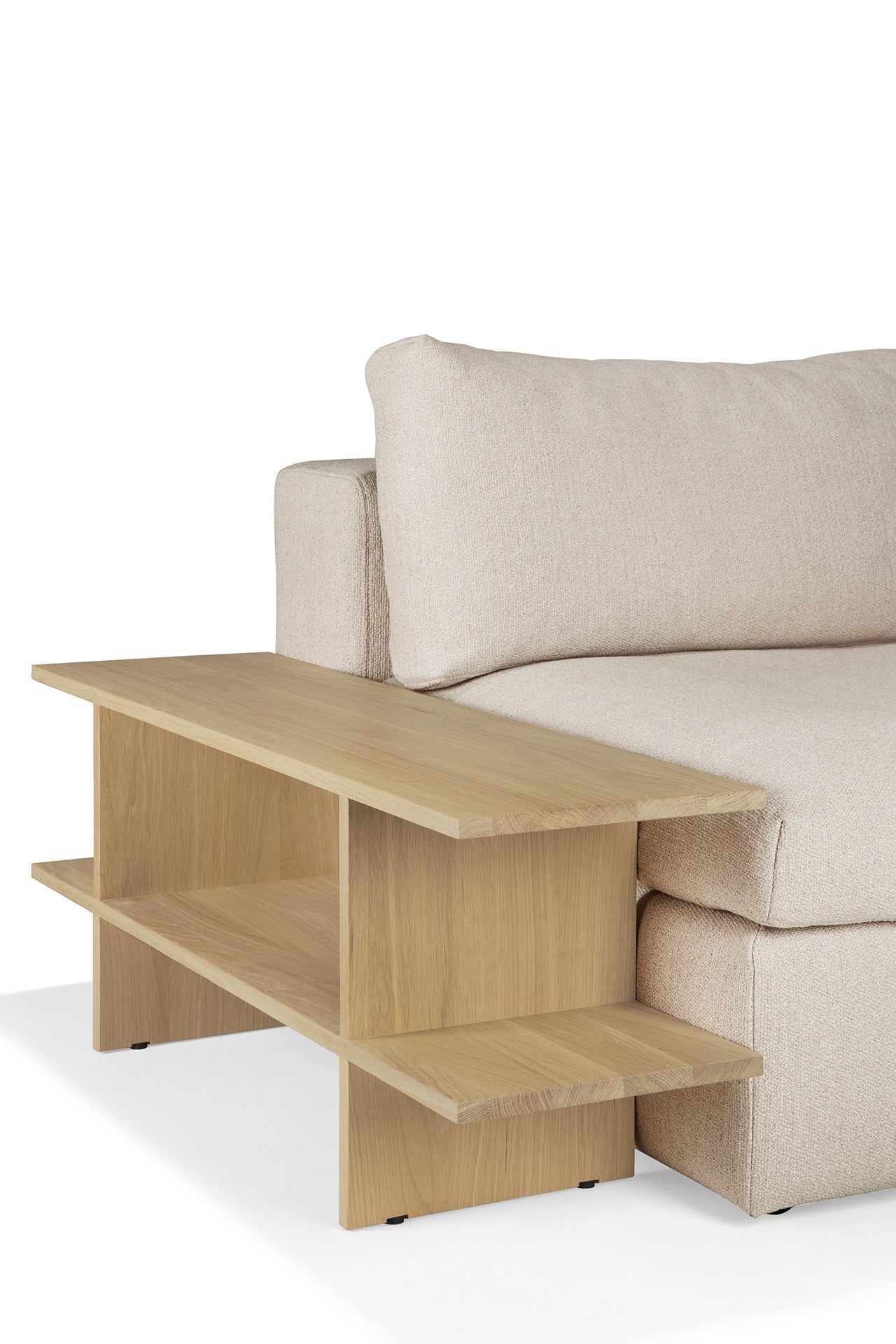 A beige upholstered sofa pairs with the Ethnicraft Kabuki Side Table – Oak, featuring two open shelves and a modern minimalist look. Crafted from solid oak, the table aligns seamlessly with the sofa’s armrest for style and function.