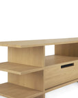 Ethnicraft Kabuki TV cupboard in light oak, featuring open shelves on the left, a solid top, and a drawer with a black handle on the right, set against a plain white background.