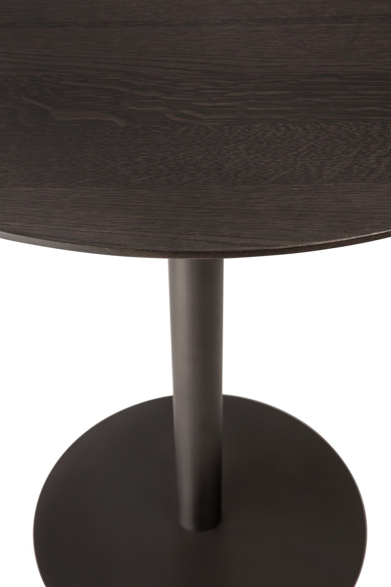 A close-up of the Ethnicraft Blend Dining Table - Brown Oak showcases its dark round tabletop with interchangeable tops and a central metal pedestal base, set against a white background.