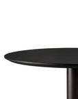 Close-up of the Ethnicraft Blend Dining Table - Black Oak, showcasing its modern round black top and cylindrical base against a plain white background.