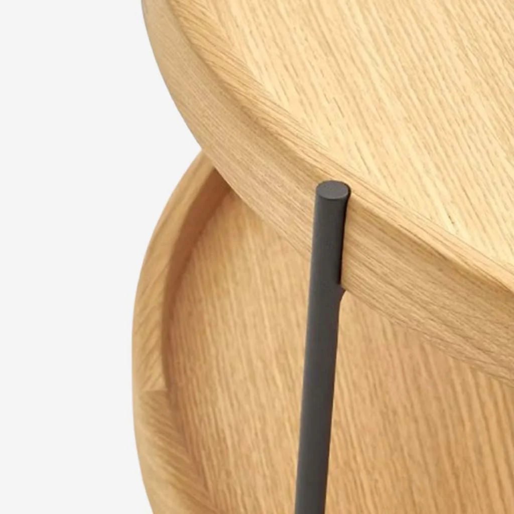 Close-up of two stacked Humla Round Side Tables by Wooden Stories, featuring raised edges and Danish-inspired design, with round wooden tops supported by a vertical black metal rod, shown against a plain white background.