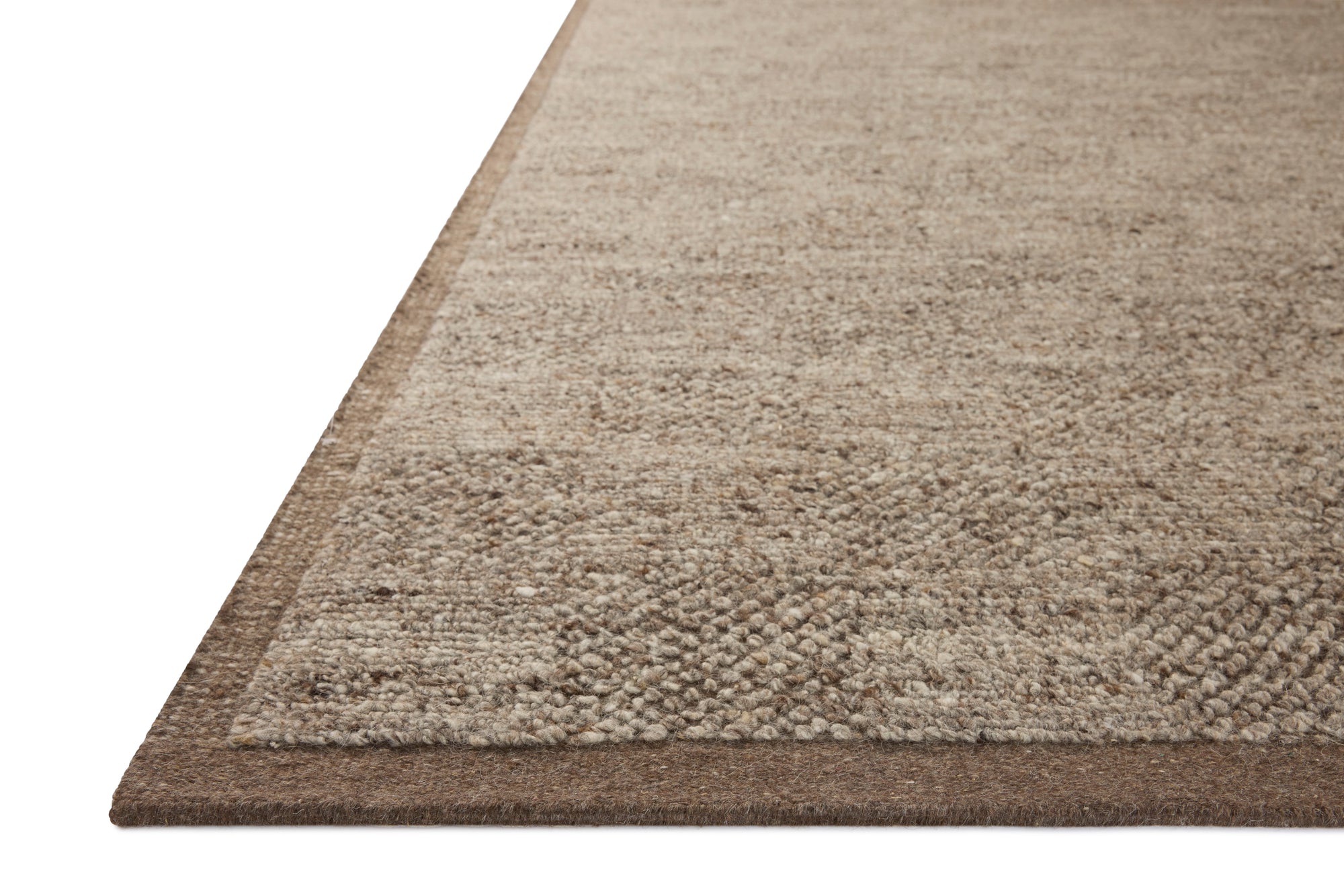 Close-up of the corner of the Alina Rug - Bark by Loloi, featuring a beige and light brown woven pattern with a dark brown border and finished edge, displayed on a white background.