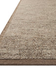 Close-up of the corner of the Alina Rug - Bark by Loloi, featuring a beige and light brown woven pattern with a dark brown border and finished edge, displayed on a white background.
