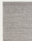Close-up of the Sherpa Rug - Pumice by Armadillo&Co, featuring a textured, light gray handwoven wool surface with a subtle diamond pattern, shown from the top left corner against an off-white background.