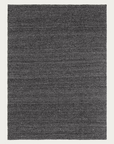 A rectangular Sherpa Rug in charcoal, handwoven from wool by Armadillo&Co, featuring a subtle textured pattern on a light background.
