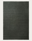 A rectangular Sherpa Rug - Kelp by Armadillo&Co, featuring a textured, hand-woven wool surface in dark gray, is displayed on a plain white background.