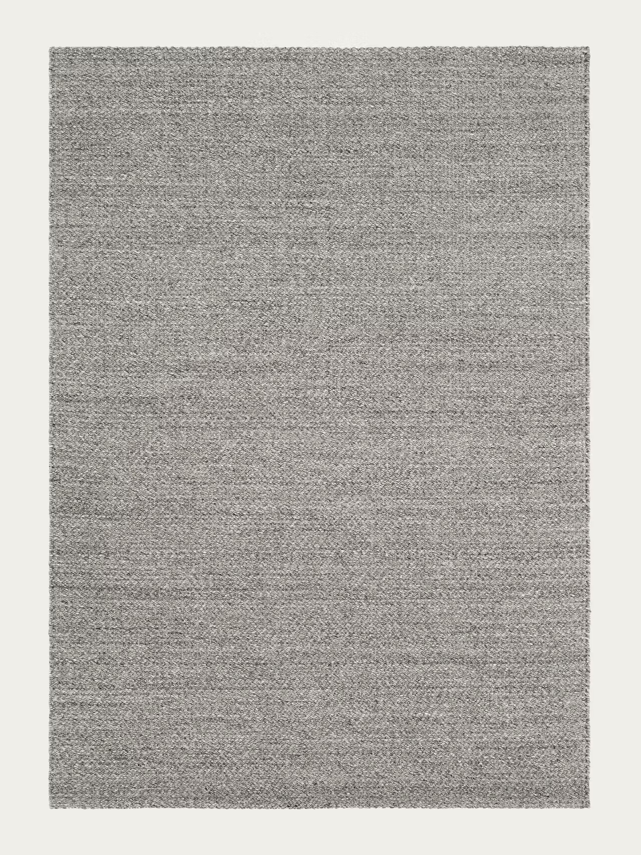 The Sherpa Rug - Pumice by Armadillo&Co is a rectangular, handwoven gray wool rug featuring a subtle woven texture, shown against a plain white background.