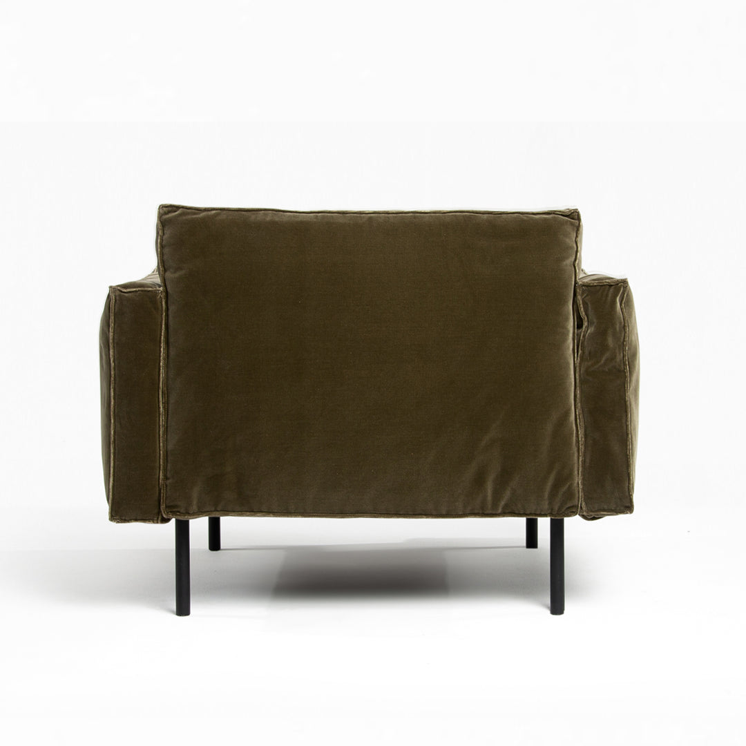 The Attendant Lounge Chair by Wooden Stories is shown from the back in green velvet fabric, with a boxy shape, wide arms, and slim black metal legs, set against a plain white background.