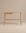 The Author Desk | Light Oak by Wooden Stories is a minimalist Danish office desk, expertly crafted from solid wood. It features four rounded legs, a flat rectangular tabletop, and a small drawer on the left side. Set against a plain beige background, the neutral tones of this refined desk create an elegant and understated workspace.