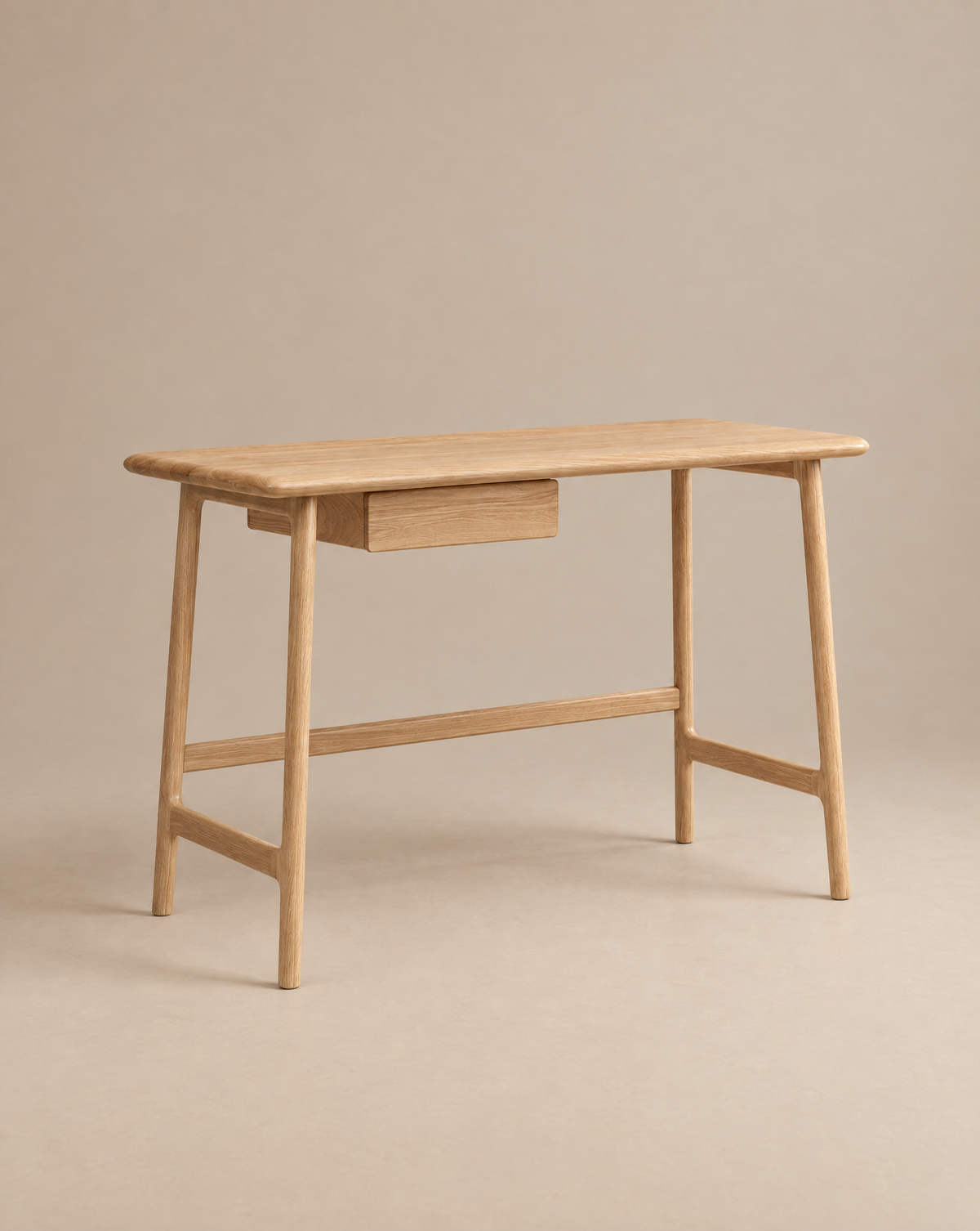 The Wooden Stories Author Desk in light oak features angled legs and a single central drawer, shown against a neutral beige background.