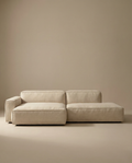 The Wooden Stories Baker Modular Sofa | Fabric • M4 showcases wide, low-profile cushions and an attached chaise in beige, blending seamlessly with a matching beige wall and floor for a modern, minimalist look.
