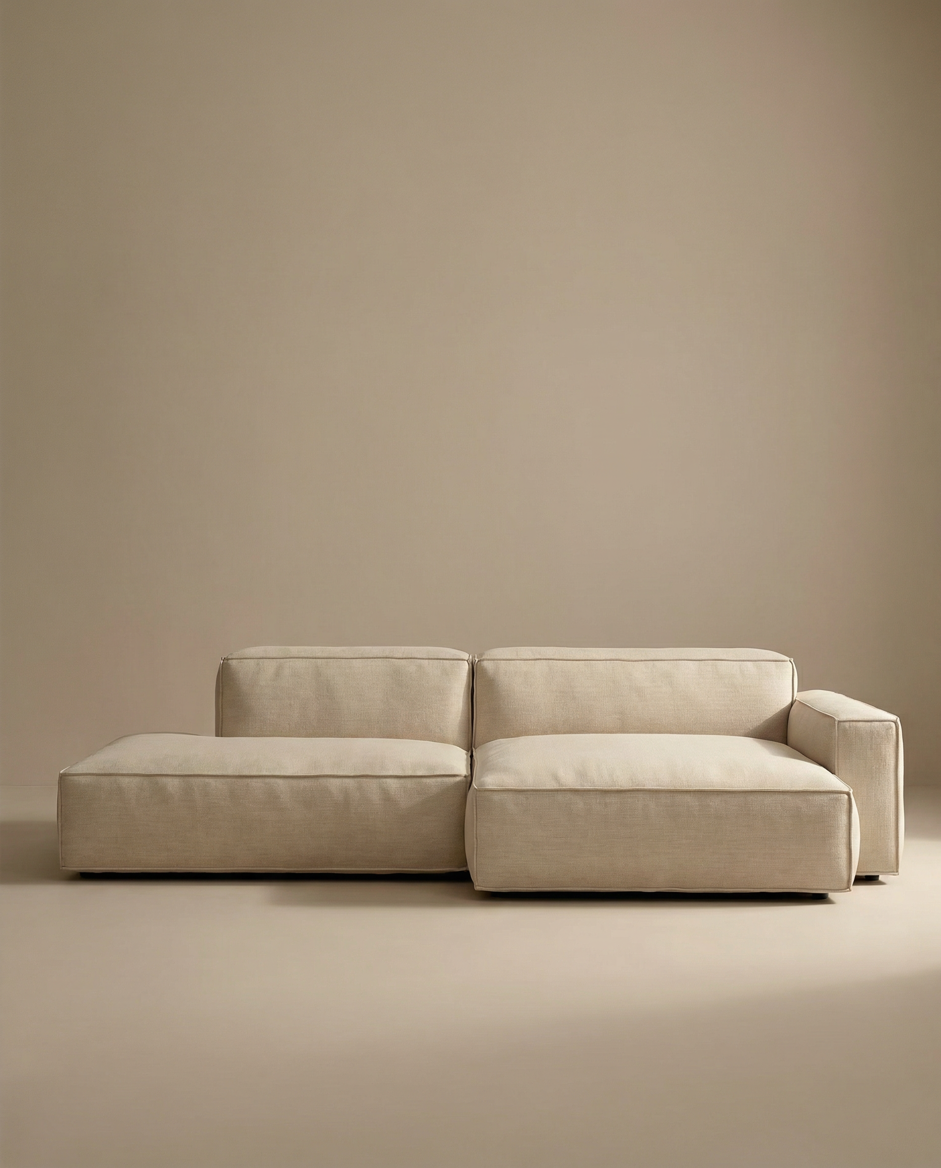 The Wooden Stories Baker Modular Sofa | Fabric • M4, featuring clean lines and low seating in minimalist beige, is styled against matching beige walls and floors for a simple, modern look.