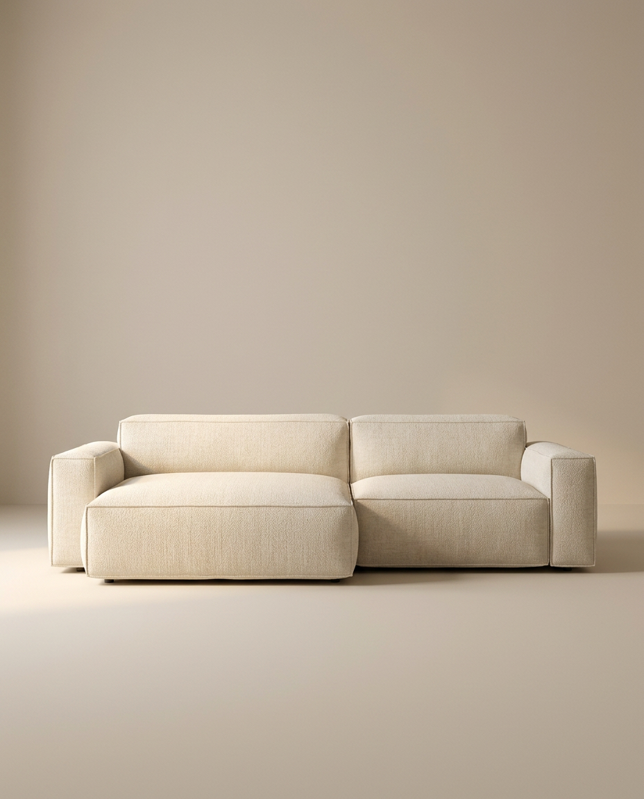 The Baker Modular Sofa | Fabric • M3 by Wooden Stories features a modern, minimalist beige design with wide armrests and a low backrest, showcased against a plain, neutral-colored background.